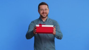 Mutlu gülümseyen orta yaşlı bir adam doğum günü hediyesi kutusunu sunar, hediye paketini uzatır, hediye ikramiyesi teklif eder, Noel indirimini kutlar. Mavi arka plandaki adam