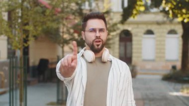 Hoşnutsuz, kötü bir fikre tepki veren, kötü kaliteden memnun olmayan, el sallayan, başını sallayan beyaz bir adam. Şehir sokağında genç bir gezgin..