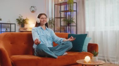 Sakin ol, sakin ol. Kafkasyalı genç bir kadın müzik dinliyor, derin derin nefes alıyor, gözleri kapalı konsantre düşüncelerle meditasyon yapıyor, evdeki kanepede oturuyor. Oturma odasındaki kız.