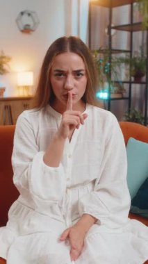 Sessiz olun lütfen, sessiz olun. Genç bir kadının portresi işaret parmağını dudaklarına bastırıyor. Sessiz ol işareti yapıyor. Evdeki dedikodu sırrını kimseye söyleme. Kanepede oturan güzel kız. Dikey