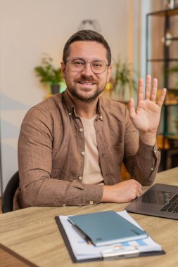 Hoş geldiniz. Kafkas 'lı mutlu iş adamı el sallayarak selam veriyor. Birine hoş geldin diyor. İnternetteki Webinar, uzaktan konuşma. Ofisteki bilgisayarla masa başında oturan serbest çalışan bir adam..