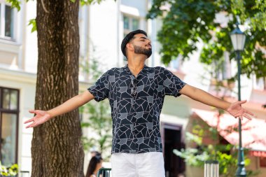 Hintli genç adam derin bir nefes alıyor, dinleniyor, dinleniyor, meditasyon yapıyor, dışarıda sakinleşiyor. İspanyol adam şehir parkında mutlu günlerin tadını çıkarıyor. Kasaba yaşam tarzları