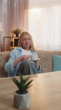 Evde sıcak kahve içen bir kadın, yavaşça yudumlarken gözlerini kapayan bir kadın. Kanepede oturan bir kız canlanıyor. Sessizlikten keyif alıyor. Sabahın erken saatlerinde pozitif havayla harmanlıyor.