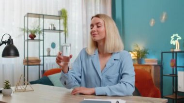 Susamış genç bir kadın elinde bir bardak doğal filtrelenmiş su tutarak susuz kalmadan su içiriyor. Ters osmoz filtresinden sonra su. İyi yaşam alışkanlıkları olan sarışın bir kız sağlıklı bir hayat sürüyor..