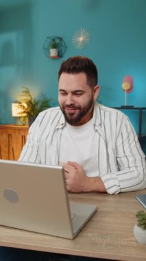 Kafkasyalı genç serbest çalışan laptop ekranına bakıyor, arkadaşlarıyla ya da ailesiyle hoş sohbetin tadını çıkaran bir video kamera konferansı yapıyor. Ofisteki masa başında oturan adam. Dikey