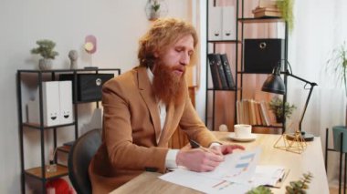 Kendine güvenen iş adamlarından oluşan POV raporları ve grafikleri ofis masasında gösteriyor. Kızıl saçlı adam video görüşmesi sırasında projeyi tartışıyor. Sakallı serbest çalışan kameraya bakıyor. Web kamerası görünümü.