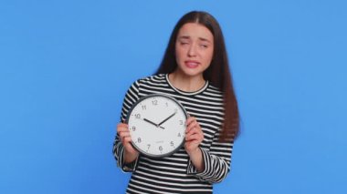 Kafkasyalı bir kadın, anksiyete kontrol saati, işe geç kalma, gecikme, teslim tarihi. Stüdyonun mavi arka planında dakikalar, dakikalar süren bir izolasyona bakıyor.