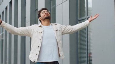 Genç Hintli adam derin bir nefes alıyor, dinleniyor, dinleniyor, meditasyon yapıyor, dışarıda sakinleşiyor. Arap Hindu adam şehir merkezinde mutlu bir gün geçiriyor. İş adamları