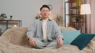 Sakin ol, sakin ol. Evdeki koltukta oturan orta yaşlı bir adam derin derin nefes alıyor, gözleri kapalı, konsantre düşüncelerle meditasyon yapıyor, huzurlu bir zihin, müzik dinliyor. Oturma odasında olgun bir adam..