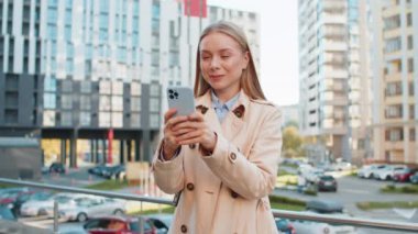Kafkasyalı yetişkin bir iş kadını cep telefonuyla internette sohbet ediyor mutlu bir orta yaşlı kadın cep telefonu kullanıyor, şehir merkezindeki caddede SMS ile iletişim kuruyor..