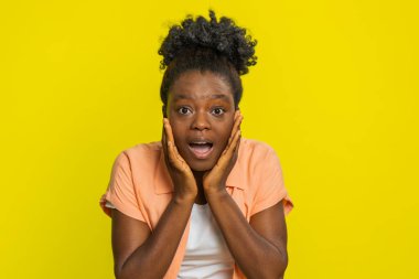 Aman Tanrım, vay canına. Heyecanlı afro-amerikan kadın kameraya büyük gözlerle bakıyor başarıyı kutlayan ani zaferin şokuyla iyi haberler. Sarı arka planda sürpriz bir kız.