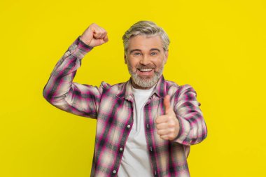 Beyaz, orta yaşlı bir adam başarı zaferini kutluyor. Piyango vurgununu başarıyla kazanıyor. Oyun oynuyor, iyi haberler, zafer. Yetişkin bir adam sarı arka planda kapalı yerde izole edilmiş.