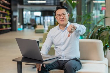 Hoşlanmamak. Ofis lobisinde dizüstü bilgisayarla çalışan üzgün bir işadamı işaret dilini gösteriyor, hoşnutsuzluğunu, memnuniyetsizliğini ve kötü işini ifade ediyor. Otel odasında hoşnutsuz ciddi bir adam var..