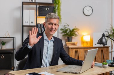 Hoş geldiniz. Mutlu genç işadamı el sallıyor. El sallıyor. Birisini selamlıyor. Takım elbiseli serbest çalışan adam ofisteki laptopuyla masada oturuyor.