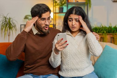 Hayal kırıklığına uğramış çok ırklı çift, evdeki kanepede otururken akıllı telefondan kötü haberler okuyorlar. Hüzünlü genç aile, acı verici bir mesajla bunalıma giriyor.