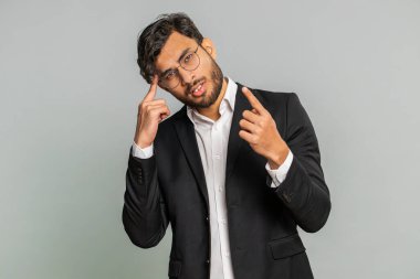 Düşünmem gerek. Düşünceli Hintli iş adamı şüphesi, kafa yormak, hayal etmek, zor çözümleri merak etmek, kafası karışmış hissetmek, seçim konusunda emin olmak. Erkek Arap erkek, gri arka planda izole edilmiş.