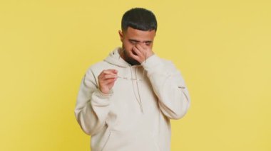 Yorgun düşmüş Hintli genç adam gözlüklerini çıkarıyor, göz ağrısı çekiyor, uzun çalışma saatleri yüzünden fazla yoruluyor. Stüdyonun sarı arka planında gözlerini ovuşturan uykulu yorgun Arap adam.