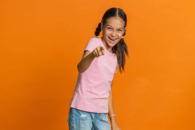 Çocukluk çağındaki mutlu çocuk, komik fıkraya verilen komik anekdot reaksiyonunu duyduktan sonra kahkahalarla gülüyor. Pozitif insanlar. Stüdyo turuncu arka planda izole edilmiş genç çocuklar.