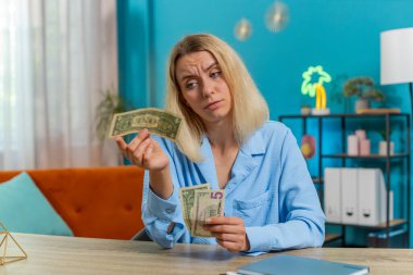 Kafkasyalı serbest çalışan genç bir kadın nakit parasız sayıyor. Finansal kriz. İflas. Yoksulluk ve yoksulluk. Kadın iş kadını oturma odasındaki ofis masasında oturuyor..