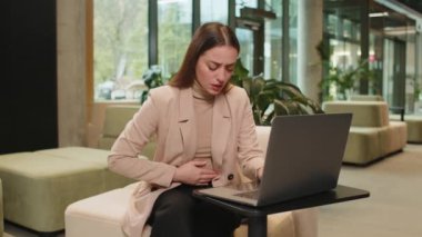 Ofis lobisinde laptopta çalışırken aşırı yemek yiyen Kafkasyalı iş kadını hayal kırıklığına uğramış. Acı çeken, karın ağrısı, regl sancısı çeken, regl sancısı çeken kadın yönetici..