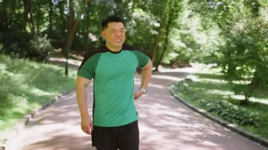 Sırt ağrısı, spor sakatlığı, parkta kas spazmı geçiren genç bir Asyalı koşucu. Spor kıyafetli yakışıklı bir adam güneşli bir yaz gününde sırt ağrısı ve idmandan sonra dışarıda sorun yaşıyor..