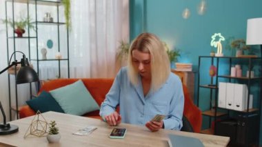 Planlama bütçesi. Zengin, mutlu, beyaz bir kadın nakit sayıyor, akıllı telefon hesap makinesi kullanıyor, ev faturalarını hesaplıyor. Gelir getiren, kazanan, planlanan tatil için para biriktiren bir kız..