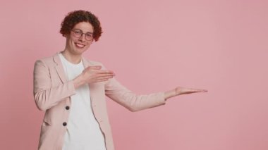 Beyaz tenli çekici bir adam aferin diyor ve reklam reklamları için reklam alanı olarak boş bir yeri gösteriyor. Adam pembe arka planda izole edilmiş. Yaşam biçimi