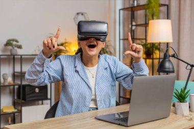Evde ofis masasında otururken VR kulaklığı test eden Hintli serbest çalışan sürpriz bir kadın. Evde uzaktan kumanda ile çalışan genç işadamı kız sunum yapıyor. Yaşam biçimi.