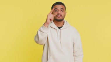 Sen delisin, aklın yerinde değil. Kafası karışmış Hintli bir adam kamerayı işaret edip aptalca bir jest yapıyor, aptal bir planı sorup kabadayılık taslıyor. Sarı stüdyo arka planında izole edilmiş bir Arap.