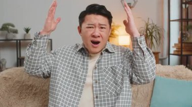 Yüzünü buruşturan Çinli bir gencin portresi. Sıkılmış, hayal kırıklığına uğramış, kötü haber. Üzgün adam TV seyrediyor. Utanmış ve sinirlenmiş. Evdeki kanepede oturmuş kameraya bakıyor..