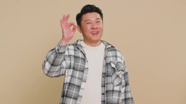 - Tamam. Mutlu Asyalı orta yaşlı bir adam kameraya bakıp olumlu bir tavır sergiliyor olumlu bir geri bildirim yapıyor iyi bir şey onaylıyor, zaferi kutluyor. Bej arka planı olan olgun bir Çinli.