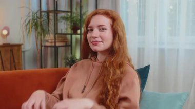 Ben de seni seviyorum. Oturma odasındaki kanepede oturan mutlu, beyaz saçlı genç bir kadının portresi aşkın sembolünü yapar, kameraya kalp işaretini gösterir, romantik duygular ifade eder, samimi olumlu duygular ifade eder..