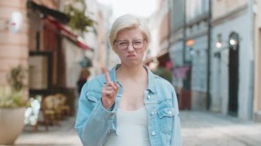 Hoşnutsuz, kötü bir fikre tepki veren, kötü kaliteden memnun olmayan beyaz bir kadın, el salla, başını salla hayır, reddet fikri, evlenme teklifini sevme. Genç sarışın bayan gezgin şehir caddesinde