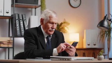 Kafkasyalı kıdemli işadamı serbest çalışan büyükbaba akıllı telefon daktilo kullanıyor, piyango oyunu sonuçlarını kaybediyor, kötü haber, servet kaybı, çalışma masasında başarısız oluyor.