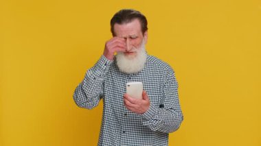 Üzgün son sınıf öğrencisi akıllı telefon daktilo kullanıyor, oyun oynuyor, kaybediyor, piyango yüzünden şaşırıyor kötü talih kaybı şanssız haber. Yaşlı, olgun, emekli büyükbaba sarı arka planda.