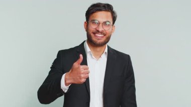 Gibi. Hintli işadamı bir şeyi onaylıyor ya da olumlu yanıt veriyor reklamlar iyi fikir geri bildirimlerini seviyor, başarı zaferini kutluyor. Gri arkaplanda izole edilmiş adam