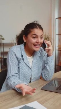 Gülümseyen Hintli serbest çalışan kız ofis masasında müşteriyle akıllı telefondan konuşuyor. Günlük giysiler içinde satış elemanı. Uzak bir iş. İşsizlik işgali. Dikey.