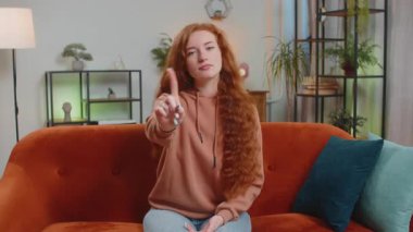 Mutsuz genç bir kadın nahoş berbat bir fikre tepki veriyor, kötü kaliteden memnun değil, el sallıyor, başını sallıyor hayır, reddet fikri, evlenme teklifini sevme. Kızıl saçlı kız sınıftaki kanepede oturuyor..