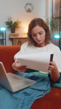 Finansal grafik belgeleriyle çalışan kadın muhasebeci, çizelgeler için vergileri hesaplayan ve kanepenin ev gelirlerinin grafiklerini çizen kadın. Laptop bilgisayarında çalışan genç bir kız, masraflar için bütçe planlıyor. Dikey