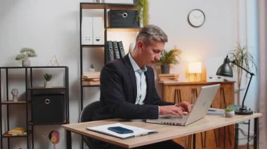 Gibi. Kafkasyalı mutlu işadamı onaylayıcı bir şekilde kameraya bakıyor ve olumlu bir işaret veriyor iyi haber olumlu geri bildirim. Genç yakışıklı adam evdeki masada oturuyor..