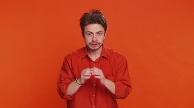 Sırlarımı sakla, sessiz ol. Kafkasyalı bir adam el ele tutuşup dedikoduları fısıldıyor. Dedikoduları paylaşıyor, sessiz. Turuncu arka planda izole edilmiş ilginç, gizli bir hikaye anlatan genç bir adam.