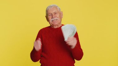 Zengin, mutlu, yaşlı bir adam hayran, başarılı iş kariyeri, piyango talihlisi, yüksek gelirli emekli maaşı gibi banknotlar sallıyor. Sarı arka planda yaşlı büyükbaba emeklisi