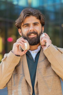 Neşeli, gevşemiş Arap iş adamı açık havada en sevilen enerjik disko rock n roll müziğini dinliyor. Yetişkin bir adam kablosuz kulaklıklarını çıkarıp şehir merkezinde gülümseyen kameraya bakıyor..