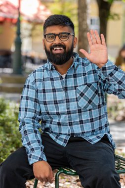 Hoş geldiniz. Hintli sakallı adam kameraya dostça gülümsüyor, el sallıyor selam veriyor, ya da veda ediyor, dışarıda misafirperver bir yüz ifadesiyle karşılıyor. Şehir sokağındaki İspanyol adam. Dikey