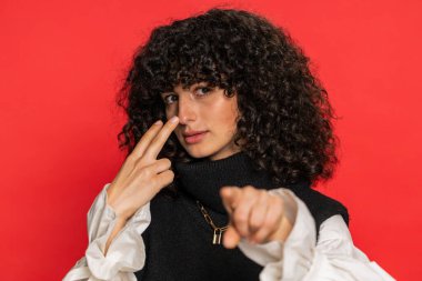 Gözüm üzerinde. Özenli, beyaz, kıvırcık saçlı, gözleri ve kamerası olan genç bir kadın. Seni birini gözetlerken izlediğimi göster. Katı kız kırmızı arka planda izole edilmiş.