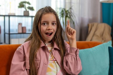 Evreka. İlham verici kız iyi bir fikir, plan, başlangıç, ilham verici motivasyon hareketi, problem çözümü gösteriyor. Evdeki oturma odasındaki kanepede oturan şık çocuk.