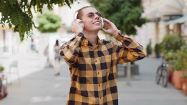 Kablosuz kulaklıkla dans eden mutlu, gevşemiş yetişkin adam açık havada en sevilen disko rock 'n roll müziğini dinliyor. Şehir Güneşi Sokağı 'nda yürüyen genç bir adam. Yaşam Tarzları.