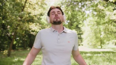 Lotus pozisyonunda oturan genç adam yaz günü şehir parkında dinleniyor. Sportif kaygısız adam yoga meditasyonu yapıyor, pozitif enerji alıyor, sağlıklı yaşam tarzı var. Aktif rahatla sporcu.