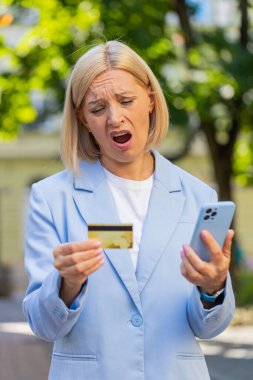 Hüsrana uğramış iş kadını, şehir caddesinde duran cep telefonundan kredi kartını kontrol ederken dolandırıcılığı keşfetti. Üzgün kadın işveren aldatma kurbanı oldu, hesabından para çalındı..
