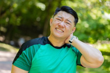 Spor Asyalı koşucunun omuz ağrısı ve sakatlık konsepti var. Fitness kaslı Japon erkeğin kolunda bir ağrı olduğu için boynu ve omuzları ağrıyor. Sporcu dışarıda eklemlerinde ağrı var..